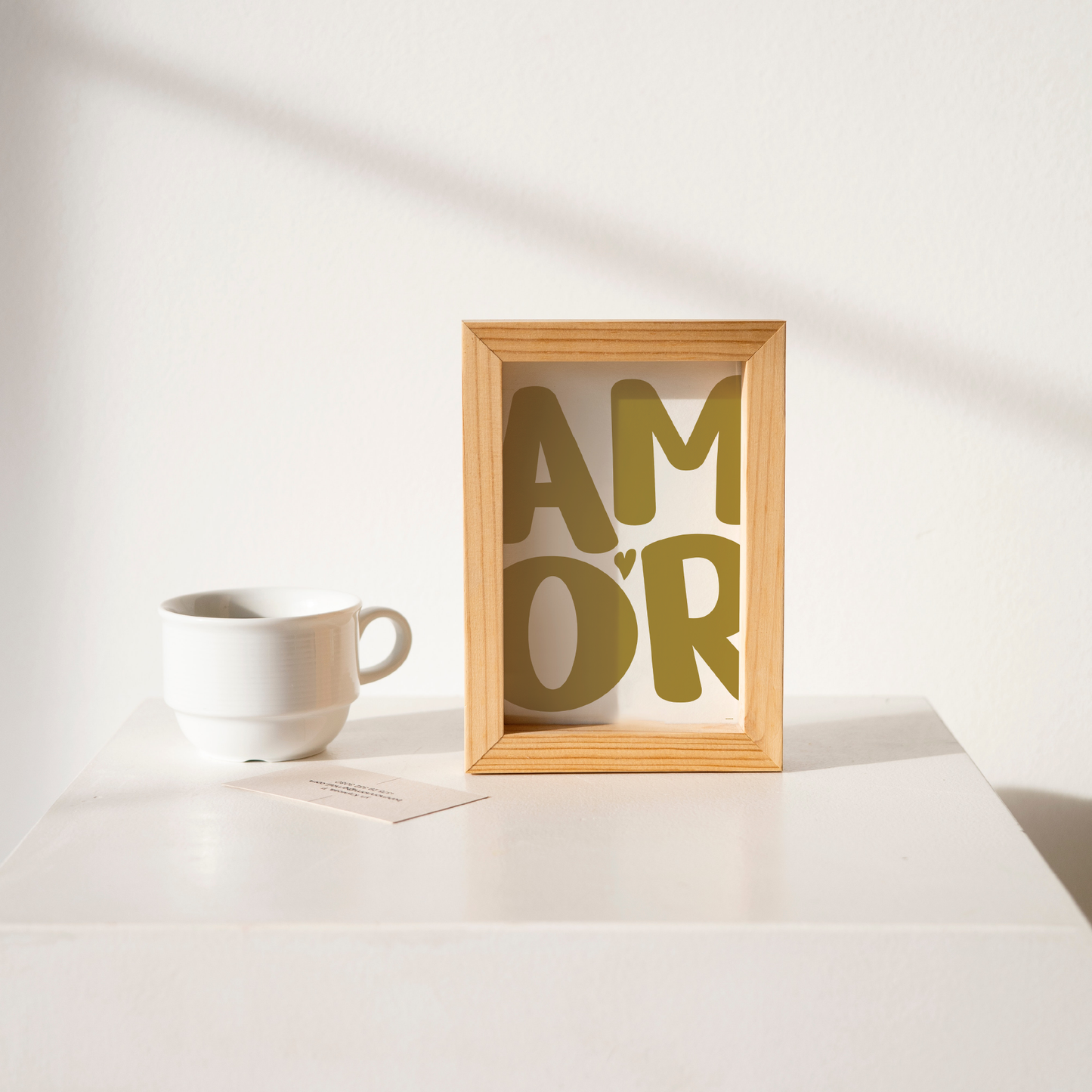 Small 'AMOR' Modern Aesthetic Wall Art Print in warm green on white. Framed cute wall decor on a clean white table.