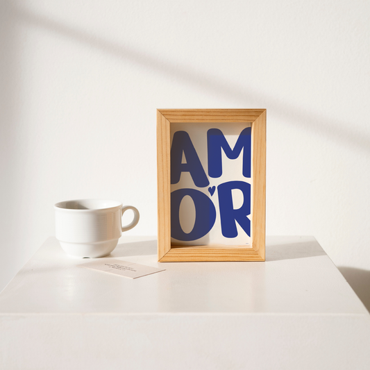 Small 'AMOR' Modern Aesthetic Wall Art Print in bold blue on white. Framed cute wall decor on a clean white table.