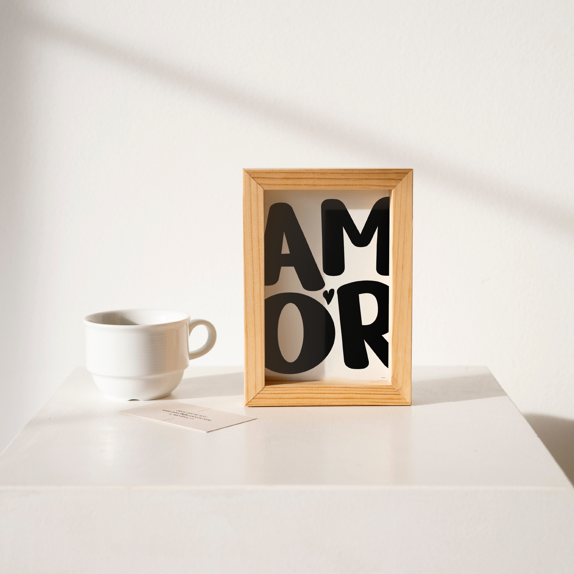 Small 'AMOR' Modern Aesthetic Wall Art Print in bold black on white. Framed cute wall decor on a clean white table.