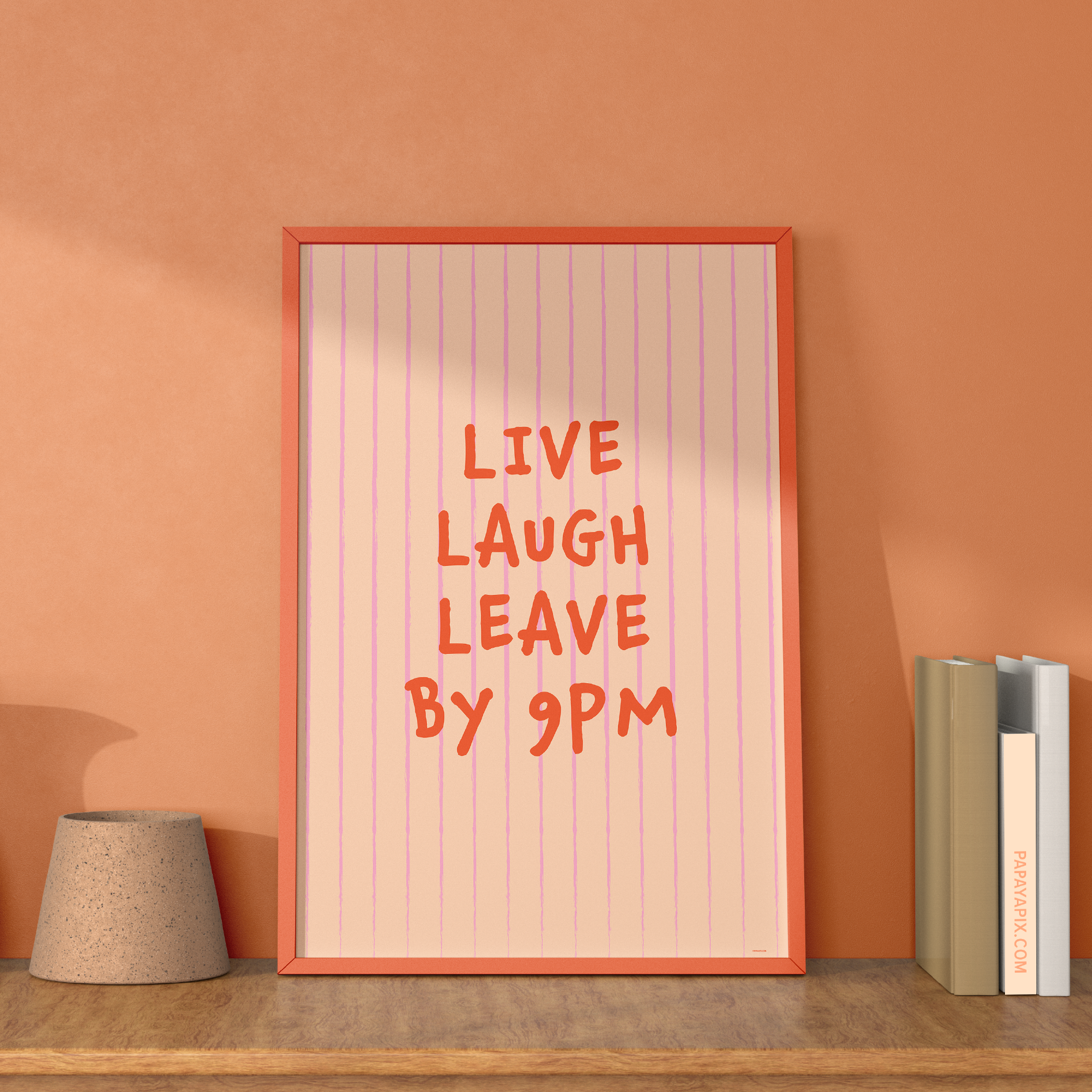 Large "Live, Laugh, Leave by 9 PM" Wall Art Print in pink. Framed cute wall decor / entryway artwork next to some books, leaning against an orange wall.