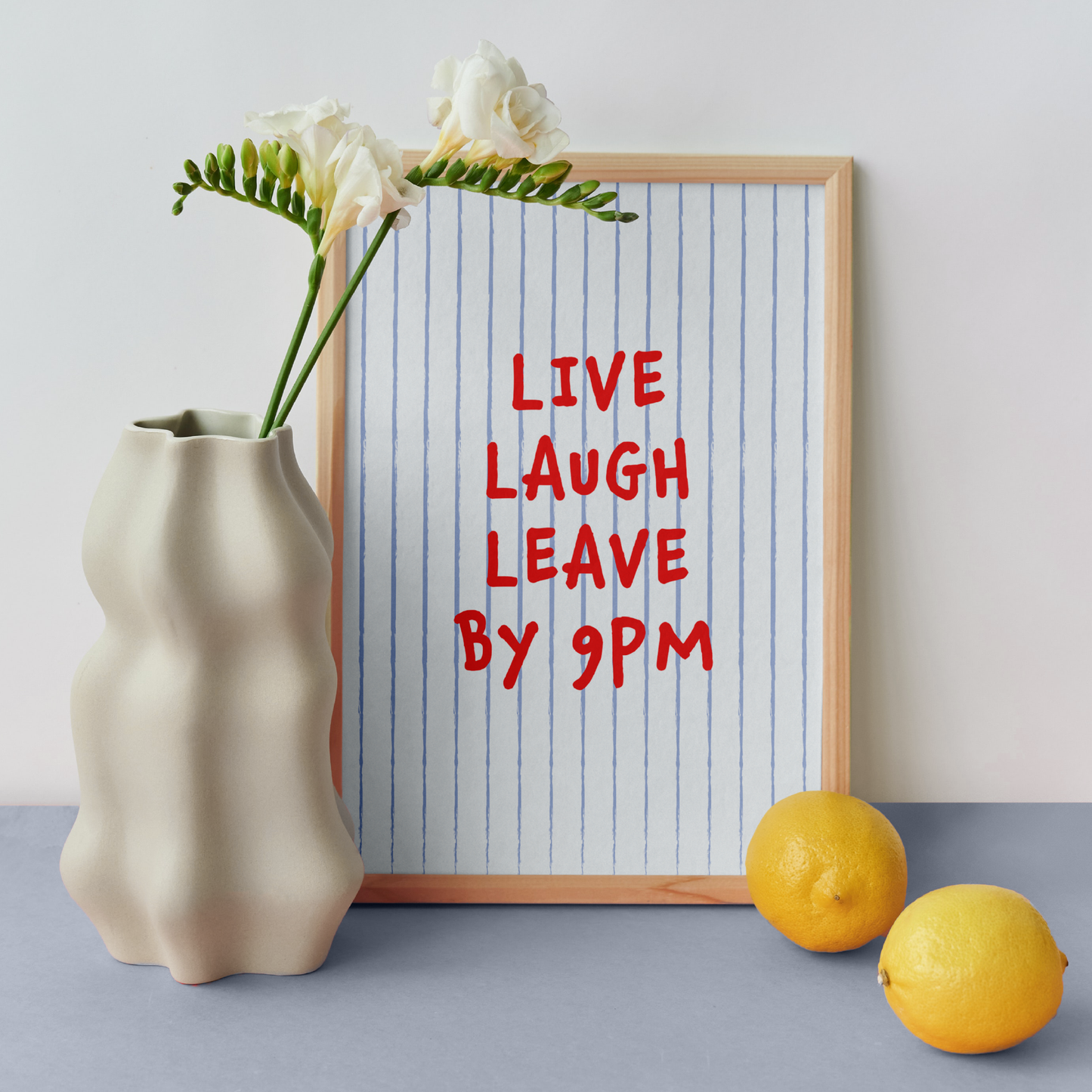 Medium "Live, Laugh, Leave by 9 PM" Wall Art Print in light blue with red words. Framed cute wall decor / entryway artwork next to a white vase.